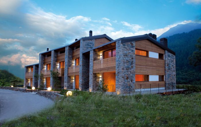 Modernes Holzhaus im Pinzgau mit Natursteinfassade, Balkon und Beleuchtung, Neubau Holzbau
